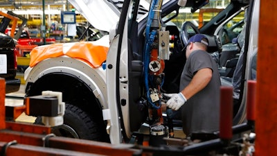 In this Sept. 27, 2018, file photo a United Auto Workers assemblyman installs the front doors on a 2018 Ford F-150 truck being assembled at the Ford Rouge assembly plant in Dearborn, Mich. On Thursday, Nov. 1, the Institute for Supply Management, a trade group of purchasing managers, issues its index of manufacturing activity for October.