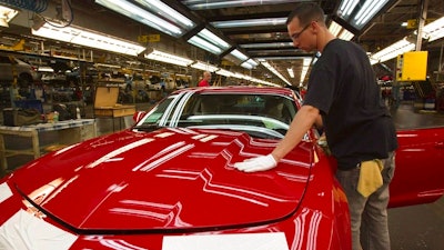 In this June 10, 2011, file photo, a worker checks the paint on a Camaro at the GM factory in Oshawa, Ontario. General Motors is closing a Canadian plant at the cost of about 2,500 jobs, but that is apparently just a piece of a much broader, company-wide restructuring that will be announced as early as Monday, Nov. 26, 2018.