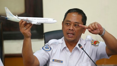 National Transportation Safety Committee investigator Nurcahyo Utomo holds a model of an airplane during a press conference on the committee's preliminary findings on their investigation on the crash of Lion Air flight 610, in Jakarta, Indonesia, Wednesday, Nov. 28, 2018. Black box data collected from their crashed Boeing 737 MAX 8 show Lion Air pilots struggled to maintain control as the aircraft's automatic safety system repeatedly pushed the plane's nose down, according to a preliminary investigation into last month's disaster.
