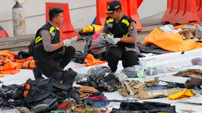 Members of police forensic team inspect personal belongings retrieved from the waters where Lion Air flight JT 610 is believed to have crashed, at Tanjung Priok Port in Jakarta, Indonesia, Wednesday, Oct. 31, 2018. A massive search effort has identified the possible seabed location of the crashed Lion Air jet, Indonesia's military chief said Wednesday, as experts carried out the grim task of identifying dozens of body parts recovered from a 15-nautical-mile-wide search area.