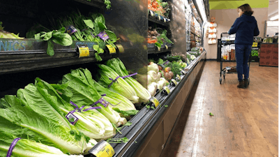 In this Nov. 20, 2018 file photo, romaine lettuce sits on the shelves as a shopper walks through the produce area of an Albertsons market in Simi Valley, Calif. After repeated food poisoning outbreaks linked to romaine lettuce, the produce industry is confronting the failure of its own safety measures in preventing contaminations. The latest outbreak underscores the challenge of eliminating risk for vegetables grown in open fields and eaten raw. It also highlights the role of nearby cattle operations and the delay of stricter federal food safety regulations.
