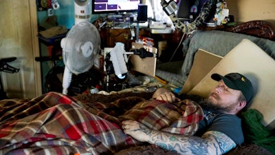 In this Friday, Nov. 16, 20158 photo, Jim Taft watches The History Channel from the confines of his bed at his home in West Columbia, S.C. Taft has experienced debilitating health issues after a neurosurgeon implanted Boston Scientific's Precision spinal cord stimulator in his back in 2014.