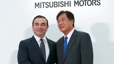 In this Oct. 20, 2016, file photo, Nissan Motor Co. President and CEO Carlos Ghosn, left, and Mitsubishi Motors Corp. Chairman and CEO Osamu Masuko pose for photographers after their joint press conference at the Nissan headquarters in Yokohama, near Tokyo. The board of Mitsubishi Motors is meeting Monday, Nov. 26, 2018, to decide whether to oust Carlos Ghosn as chairman at the Japanese automaker, which is allied with Renault-Nissan.