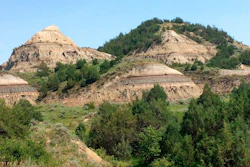 In this July 5, 2018, file photo, eroded hills are shown in Theodore Roosevelt National Park in western North Dakota. Attorneys for North Dakota's Health Department say the agency didn't improperly discount its own concerns about a proposed oil refinery near the park when it permitted the project earlier this year. The department and developer Meridian Energy Group want a state judge to reject a challenge by environmental groups to an air quality permit that allowed the company to begin construction last summer at the Davis Refinery site about 3 miles from the park.