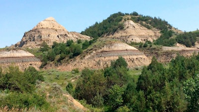 In this July 5, 2018, file photo, eroded hills are shown in Theodore Roosevelt National Park in western North Dakota. Attorneys for North Dakota's Health Department say the agency didn't improperly discount its own concerns about a proposed oil refinery near the park when it permitted the project earlier this year. The department and developer Meridian Energy Group want a state judge to reject a challenge by environmental groups to an air quality permit that allowed the company to begin construction last summer at the Davis Refinery site about 3 miles from the park.