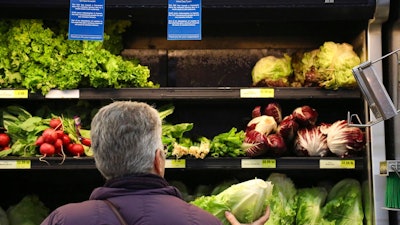 In this Nov. 20, 2018, file photo Lisa Dennis selects a head of green lettuce from the vegetable shelves at the East End Food Co-op Federal Credit Union in Pittsburgh. Health officials on Monday, Nov. 26, said it's OK to eat some romaine lettuce again. The Food and Drug Administration is narrowing last week’s alert warning people not to eat any romaine because of an E. coli outbreak. The agency hasn’t identified a source of contamination. But it says it's OK to eat romaine from parts of California and Arizona that were not harvesting when the illnesses began in October.
