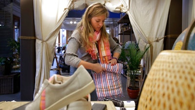 In this Tuesday, Oct. 30, 2018 photo American Rhino apparel store employee Coco Clemens, folds merchandise at a store location, in Boston. Chris Welles, owner of American Rhino, and other small business owners needing seasonal help are paying higher wages and offering bonuses as they compete with big companies for a shrinking pool of workers.