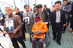 Kim Sung-joo, bottom center, a victim of Japan's forced labor, arrives at the Supreme Court's in Seoul, South Korea, Thursday, Nov. 29, 2018. South Korea's top court ordered a Japanese company to compensate 10 Koreans for forced labor during Tokyo's 1910-45 colonial rule of the Korean Peninsula.