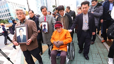 Kim Sung-joo, bottom center, a victim of Japan's forced labor, arrives at the Supreme Court's in Seoul, South Korea, Thursday, Nov. 29, 2018. South Korea's top court ordered a Japanese company to compensate 10 Koreans for forced labor during Tokyo's 1910-45 colonial rule of the Korean Peninsula.