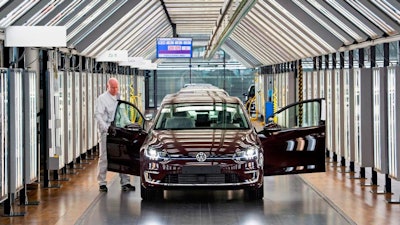In this March 5, 2018 file photo, Roland Schulz makes the final check of an e-Golf electric car in the so-called light tunnel in the German car manufacturer Volkswagen's Transparent Factory in Dresden, Germany. Volkswagen said on Wednesday, Nov. 14, 2018, that it will convert three factories in Germany to manufacture electric cars, ramping up production of zero-local emission cars ahead of tougher European emissions standards.
