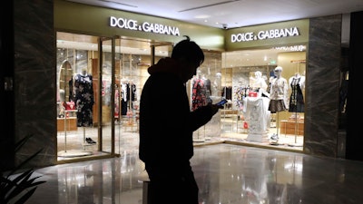 In this Nov. 21, 2018, file photo, a man walks past a Dolce&Gabbana store in Beijing, China. Dolce&Gabbana faced a boycott after Chinese netizens expressed outrage over what were seen as culturally insensitive videos promoting a major runway show in Shanghai and subsequent posts of insulting comments in a private Instagram chat.