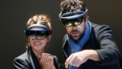 In this Sept. 24, 2017, file photo people use Microsoft Hololens to get an impression of Mercedes accessories on the stand of Mercedes-Benz during the first media day of the International Frankfurt Motor Show IAA in Frankfurt, Germany. Federal contract records show the U.S. Army has awarded Microsoft a $480 million contract to supply its HoloLens headsets to soldiers. The head-mounted displays use augmented reality, which means viewers can see virtual imagery superimposed over the real-world scenery in front of them. Microsoft says the technology will provide troops with better information to make decisions.