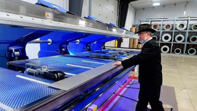 Dan Kleinsasser, of the Golden Valley Hutterite Colony near Ryegate, Mont. bends a steel roof snow dam at Valley Steel, LLC. The new venture builds custom steel siding and roofing products.