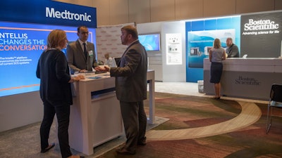 In this Saturday, Aug. 25, 2018 photo, sales representatives for Medtronic and Boston Scientific work their booths at the NYC Neuromodulation Conference in New York.