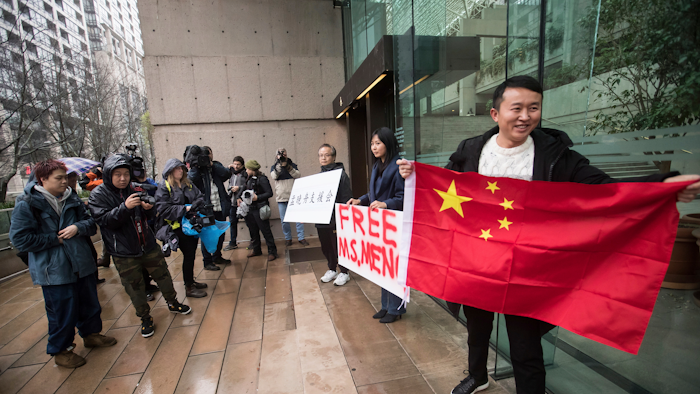 Supporters hold signs and a Chinese flag outside the British Columbia Supreme Court in Vancouver during the third day of a bail hearing for Meng Wanzhou, the chief financial officer of Huawei Technologies.