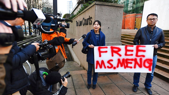People hold a sign at a Vancouver, British Columbia courthouse prior to the bail hearing for Meng Wanzhou, Huawei's chief financial officer on Monday, December 10, 2018. Meng Wanzhou was detained at the request of the U.S. during a layover at the Vancouver airport on Dec. 1.