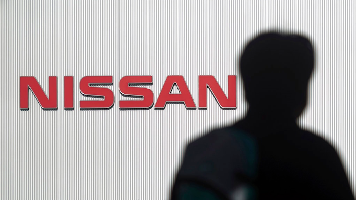 In this Nov. 21, 2018, file photo, a man walks past the logo of Nissan Motor Co. at Nissan Motor Co. Global Headquarters in Yokohama near Tokyo. Nissan, the Japanese automaker under scrutiny after its former chairman Carlos Ghosn was arrested on suspicion of financial misconduct, is recalling 150,000 vehicles spanning 11 models in Japan for dubious inspections for brakes and steering.