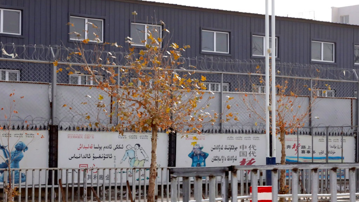 In this Wednesday, Dec. 5, 2018, photo, two layers of barbed wire fencing ring the 'Hotan City apparel employment training base' where Hetian Taida has a factory in Hotan in western China's Xinjiang region. This is one of a growing number of internment camps in the Xinjiang region, where by some estimates 1 million Muslims are detained, forced to give up their language and their religion and subject to political indoctrination. Now, the Chinese government is also forcing some detainees to work in manufacturing and food industries. Some of them are within the internment camps; others are privately owned, state-subsidized factories where detainees are sent once they are released.