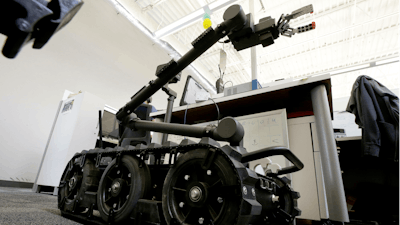 In this Aug. 28, 2018 photo a Centaur robot rests on a carpeted floor between desks at Endeavor Robotics in Chelmsford, Mass. The Army is looking for a few good robots. These robots won’t fight, at least not yet. But they will be designed to help the men and women who do. The companies making them are waging a different kind of battle. At stake is a contract worth almost half a billion dollars for 3,000 backpack-sized robots that can defuse bombs and scout enemy positions.