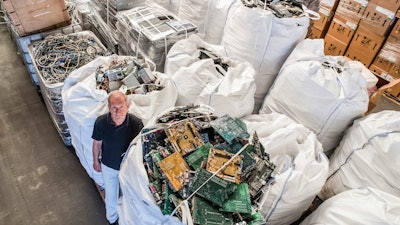 In this photo taken on July 13, 2018, founder of the company, Out Of Use, Mark Adriaenssens, stands among bags of electronic parts and components to be recycled at his warehouse in Beringen, Belgium. European Union nations are expected to produce more than 12 million tons of electronic waste per year by 2020, putting the Out Of Use company at the front of an expanding market, recuperating raw materials from electronic waste.