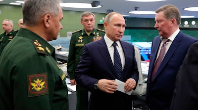 Russian Defense Minister Sergei Shoigu, left, Russian President Vladimir Putin, center, Chief of General Staff of Russia Valery Gerasimov, background center, and special representative on questions of ecology and transport, Sergei Ivanov, right, talk to each other as they come to oversee the test launch of the Avangard hypersonic glide vehicle from the Defense Ministry's control room in Moscow, Russia, Wednesday, Dec. 26, 2018. In the test, the Avangard was launched from the Dombarovskiy missile base in the southern Ural Mountains. The Kremlin says it successfully hit a designated practice target on the Kura shooting range on Kamchatka, 6,000 kilometers (3,700 miles) away.