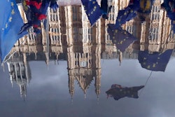 Protestors are reflected in a puddle as they wave European flags to demonstrate against Brexit in front of the Parliament in London, Monday, Dec. 3, 2018.