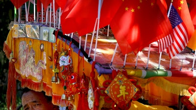 In this file photo, a driver looks out from his trishaw decorated with an American flag and Chinese flags in Beijing.