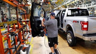 In this Sept. 27, 2018, file photo a United Auto Workers assemblyman installs the front doors on a 2018 Ford F-150 truck being assembled at the Ford Rouge assembly plant in Dearborn, Mich. On Friday, Dec. 14, the Federal Reserve reports on U.S. industrial production for November.