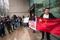 Supporters hold signs and a Chinese flag outside the British Columbia Supreme Court in Vancouver during the third day of a bail hearing for Meng Wanzhou, the chief financial officer of Huawei Technologies.