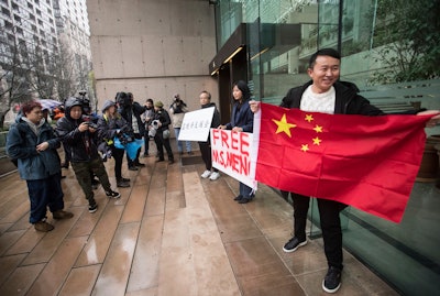 Supporters hold signs and a Chinese flag outside the British Columbia Supreme Court in Vancouver during the third day of a bail hearing for Meng Wanzhou, the chief financial officer of Huawei Technologies.