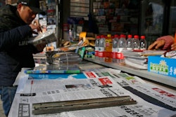 A man arranges magazines near newspapers with the headlines of China outcry against U.S. on the detention of Huawei's chief financial officer, Meng Wanzhou, at a news stand in Beijing, Monday, Dec. 10, 2018. China has summoned the U.S. ambassador to Beijing to protest Canada's detention of an executive of Chinese electronics giant Huawei at Washington's behest and demand the U.S. cancel an order for her arrest.