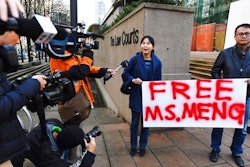 People hold a sign at a Vancouver, British Columbia courthouse prior to the bail hearing for Meng Wanzhou, Huawei's chief financial officer on Monday, December 10, 2018. Meng Wanzhou was detained at the request of the U.S. during a layover at the Vancouver airport on Dec. 1.