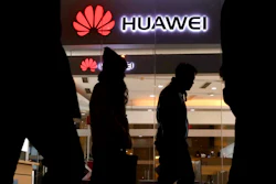 Pedestrians walk past a Huawei retail shop in Beijing Thursday, Dec. 6, 2018. China on Thursday demanded Canada release a Huawei Technologies executive who was arrested in a case that adds to technology tensions with Washington and threatens to complicate trade talks.