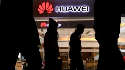 Pedestrians walk past a Huawei retail shop in Beijing Thursday, Dec. 6, 2018. China on Thursday demanded Canada release a Huawei Technologies executive who was arrested in a case that adds to technology tensions with Washington and threatens to complicate trade talks.