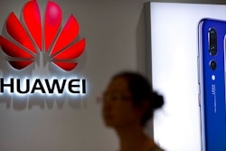 In this July 4, 2018, file photo, a shopper walks past a Huawei store at a shopping mall in Beijing. Canadian authorities said Wednesday, Dec. 5, 2018, that they have arrested the chief financial officer of China's Huawei Technologies for possible extradition to the United States.