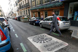 A man looks at a sign painted on the road indicating the boundary of the centre of the city as he crosses the street in Madrid, Spain, Friday, Nov. 30, 2018. Madrid activated a new traffic restriction system Friday in an attempt to reduce pollution in the city. Petrol vehicles before 2000 and diesel ones registered before 2006 are banned from this central area but on the first day of the restrictions, drivers will not be fined as municipal police were only warning drivers of the new restrictions.