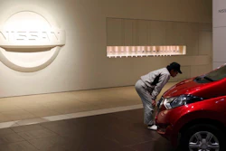 A man inspects car in front of the logo of the Nissan Motor Co. at its global headquarters in Yokohama, near Tokyo, Monday, Dec. 17, 2018. Nissan's board met Monday but failed to pick a new chairman to replace Carlos Ghosn, arrested last month on charges of violating financial regulations, saying more discussion was needed.