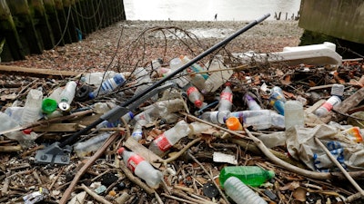 In this Feb. 5, 2018 file photo, plastic bottles and other plastics including a mop, lie washed up on the north bank of the River Thames in London. European Union officials agreed on Wednesday, Dec. 19, 2018, to ban some single-use plastics, such as disposable cutlery, plates and straws, in an effort to cut marine pollution. The measure will also affect plastic cotton buds, drink stirrers, balloon sticks, and single-use plastic and polystyrene food and beverage containers.
