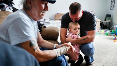 In this Nov. 28, 2018 photo, Tom Wolikow, right, holds his daughter Annabella alongside his father John, left, at their home in Warren, Ohio. It was working-class voters who bucked the area's history as a Democratic stronghold and backed Donald Trump in 2016, helping him win the White House with promises to put American workers first and bring back disappearing manufacturing and steel jobs. Whether they stick with him after this week's GM news and other signs that the economy could be cooling will determine Trump's political future.