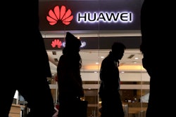 Pedestrians walk past a Huawei retail shop in Beijing Thursday, Dec. 6, 2018. China on Thursday demanded Canada release a Huawei Technologies executive who was arrested in a case that adds to technology tensions with Washington and threatens to complicate trade talks.