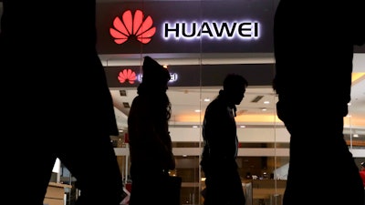 Pedestrians walk past a Huawei retail shop in Beijing Thursday, Dec. 6, 2018. China on Thursday demanded Canada release a Huawei Technologies executive who was arrested in a case that adds to technology tensions with Washington and threatens to complicate trade talks.