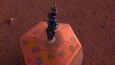 This photo provided by NASA Jet Propulsion Laboratory, shows the new Mars lander placing a quake monitor on the planet’s dusty red surface. The unprecedented milestone occurred less than a month after Mars InSight’s touchdown. InSight’s robotic arm removed the seismometer from the spacecraft deck and set it directly on the ground Wednesday, Dec. 19, 2018 to monitor Mars quakes.