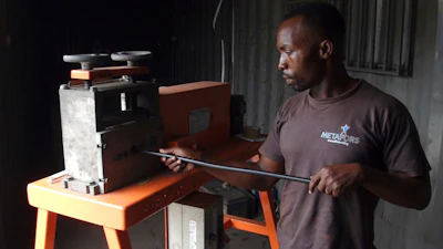 In this Nov. 26, 2018, photo, a man uses a wire-stripping machine to get to the copper and other metals in discarded electronic cables in Accra, Ghana. A safer option to burning the plastic coatings that fill lungfuls of acrid air, electrical cables are fed through the blades that slit open the plastic, making it easy to reach the copper or other metal wires inside.