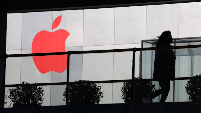 In this Dec. 6, 2018, photo, a woman runs past a Apple logo colored red in Beijing, China. Apple Inc.’s $1,000 iPhone is a tough sell to Chinese consumers who are jittery over an economic slump and a trade war with Washington. The tech giant became the latest global company to collide with Chinese consumer anxiety when CEO Tim Cook said iPhone demand is waning, due mostly to China. Weak consumer demand in the world’s second-largest economy is a blow to industries from autos to designer clothing that are counting on China to drive revenue growth.
