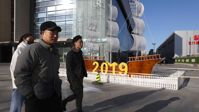 In this Friday, Jan. 4, 2019, photo, Chinese residents pass by a decor marking the new year outside a shopping mall in Beijing. A U.S. delegation led by deputy U.S. trade representative, Jeffrey D. Gerrish arrived in the Chinese capital ahead of trade talks with China. China sounded a positive note ahead of trade talks this week with Washington, but the two sides face potentially lengthy wrangling over technology and the future of their economic relationship.