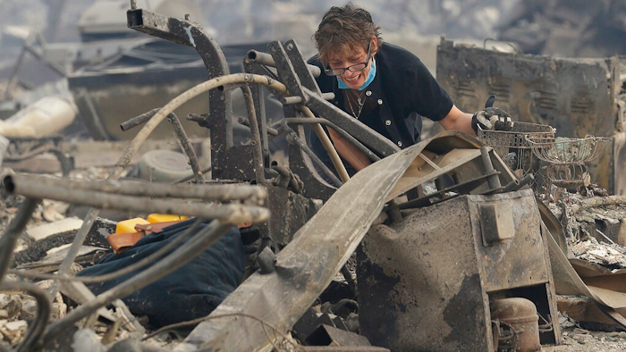 In this Oct. 9, 2017 file photo, Kristine Pond reacts as she searches the remains of her family's home destroyed by a fire in Santa Rosa, Calif. Investigators say a deadly 2017 wildfire that killed 22 people in California's wine country was caused by a private electrical system, not embattled Pacific Gas & Electric Co. The state's firefighting agency said Thursday, Jan. 24, 2019, that the Tubbs Fire started next to a residence. They did not find any violations of state law.