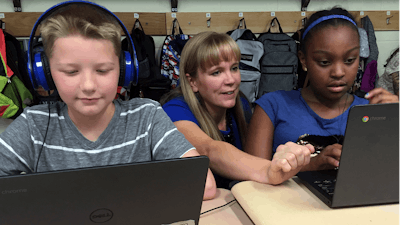 In this Sept. 20, 2018 photo, fifth grade teacher Heather Dalton, center, works with students Julian Ryno, left, and Ma'Kenley Burns, doing math problems on the DreamBox system at Charles Barnum Elementary School in Groton, Conn. A wide array of apps, websites and software used in schools borrow elements from video games to help teachers connect with students living technology-infused lives.