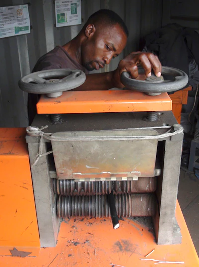 In this Nov. 26, 2018, photo, a man uses a wire-stripping machine to get to the copper and other metals in discarded electronic cables in Accra, Ghana. A safer option to burning the plastic coatings that fill lungfuls of acrid air, electrical cables are fed through the blades that slit open the plastic, making it easy to reach the copper or other metal wires inside.