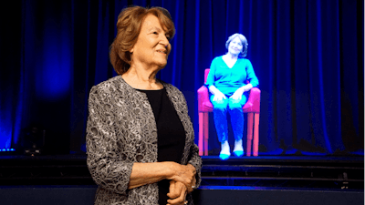 In this October 2017 photo, Holocaust survivor Fritzie Fritzshall stands in front of a hologram of herself at The Abe & Ida Cooper Survivor Stories Experience in the Illinois Holocaust Museum & Education Center in Skokie, Ill. The experience combines high-definition holographic interview recordings and voice recognition technology to enable Holocaust Survivors to tell their deeply moving personal stories and respond to questions from the audience.