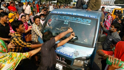 In this Wednesday, Jan. 9, 2019 file photo, Bangladeshi garment workers vandalize a vehicle during a protest in Savar, on the outskirts of Dhaka, Bangladesh. Kalpona Akter of the Bangladesh Center for Worker Solidarity said Thursday, Jan. 31, that more than 5,000 garment workers demanding wage hikes have been laid off while hundreds of them are facing police charges in the world’s second-largest garment export industry. She said the firings came after thousands of workers took to the streets earlier this month in and around Dhaka, the nation’s capital.